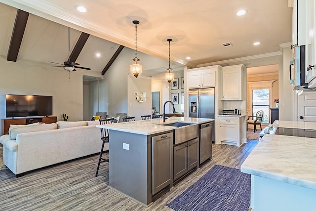 kitchen featuring a sink, stainless steel appliances, vaulted ceiling with beams, and white cabinetry