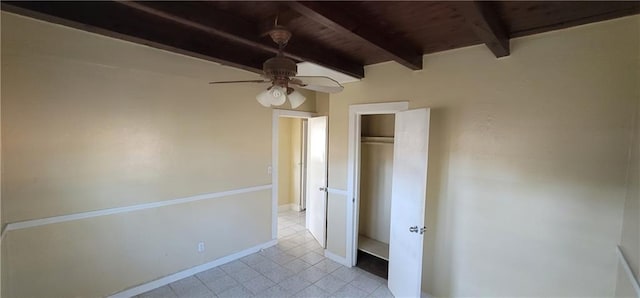 unfurnished bedroom featuring wooden ceiling, a ceiling fan, baseboards, a closet, and beamed ceiling