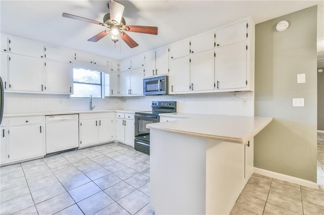 kitchen with black electric range oven, white dishwasher, kitchen peninsula, light tile patterned floors, and white cabinetry