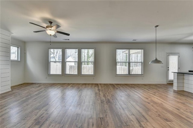 unfurnished living room featuring crown molding, wood finished floors, baseboards, and ceiling fan