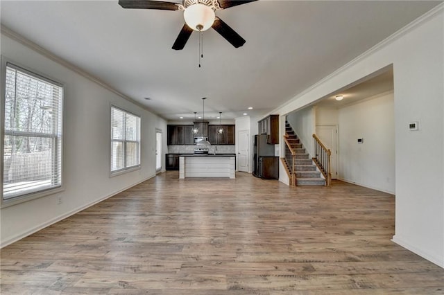 unfurnished living room featuring recessed lighting, light wood-style floors, stairs, and crown molding