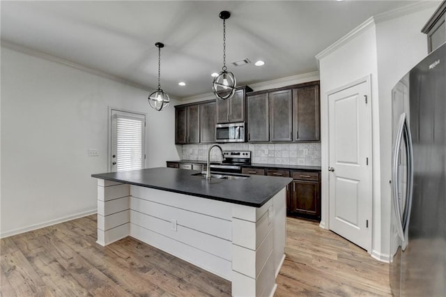 kitchen featuring a sink, stainless steel appliances, dark countertops, and ornamental molding