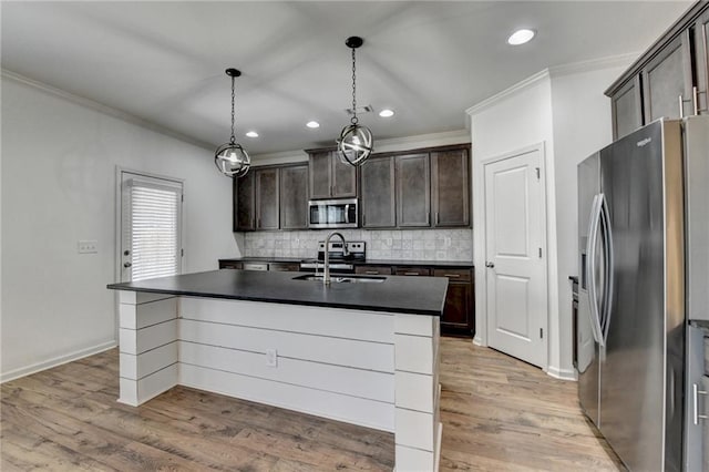 kitchen featuring dark countertops, ornamental molding, appliances with stainless steel finishes, light wood-style floors, and a sink