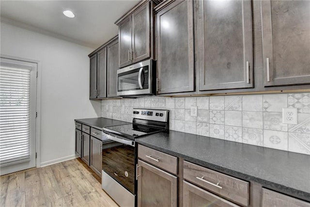 kitchen with dark countertops, tasteful backsplash, ornamental molding, light wood-style flooring, and stainless steel appliances