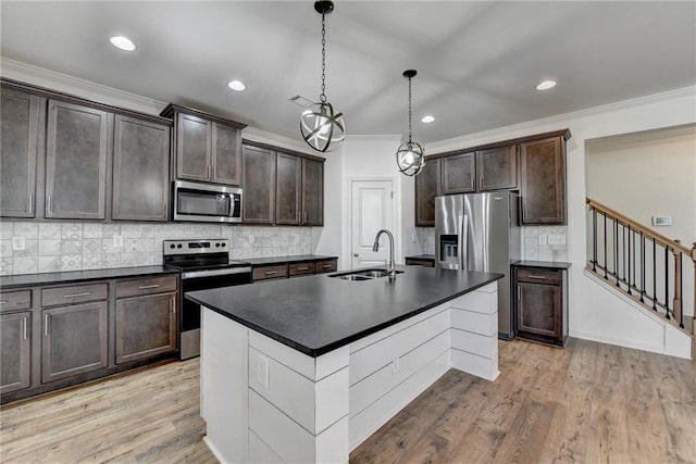 kitchen featuring a sink, stainless steel appliances, dark countertops, and light wood finished floors