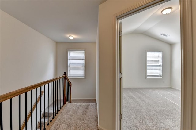 corridor featuring lofted ceiling, an upstairs landing, carpet, and visible vents