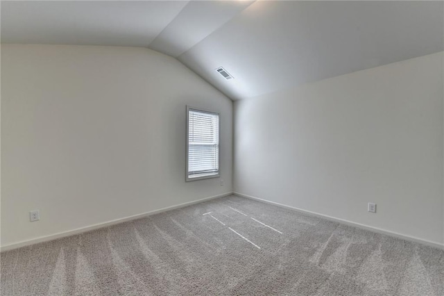 unfurnished room with visible vents, baseboards, carpet flooring, and vaulted ceiling