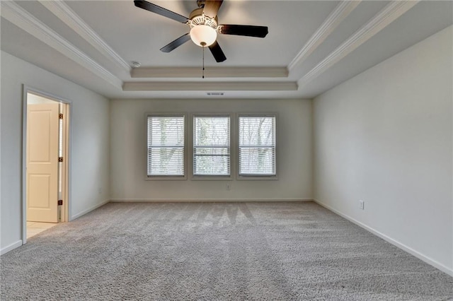 empty room with crown molding, a raised ceiling, and carpet