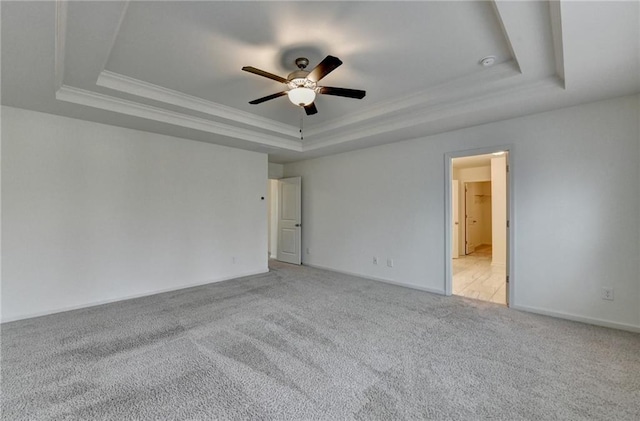 carpeted empty room with ceiling fan, a raised ceiling, baseboards, and ornamental molding