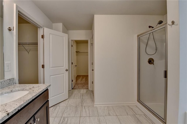 bathroom featuring a spacious closet, marble finish floor, vanity, and a shower stall