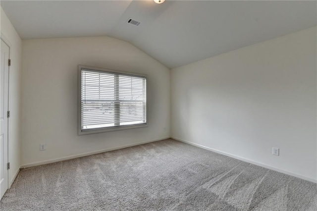 spare room with lofted ceiling, visible vents, baseboards, and carpet floors