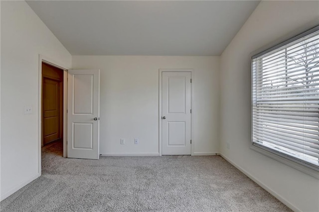 unfurnished bedroom with baseboards, carpet floors, and lofted ceiling