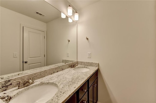 bathroom with double vanity, visible vents, and a sink