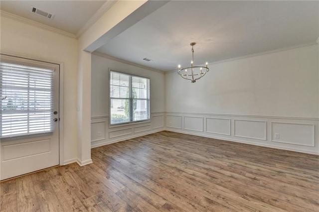 unfurnished dining area with visible vents, wood finished floors, an inviting chandelier, and ornamental molding