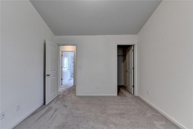 unfurnished bedroom with a spacious closet, carpet flooring, and baseboards