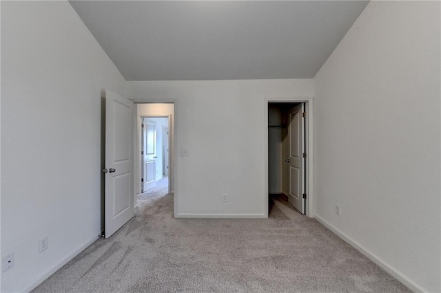 unfurnished bedroom with a spacious closet, baseboards, and carpet