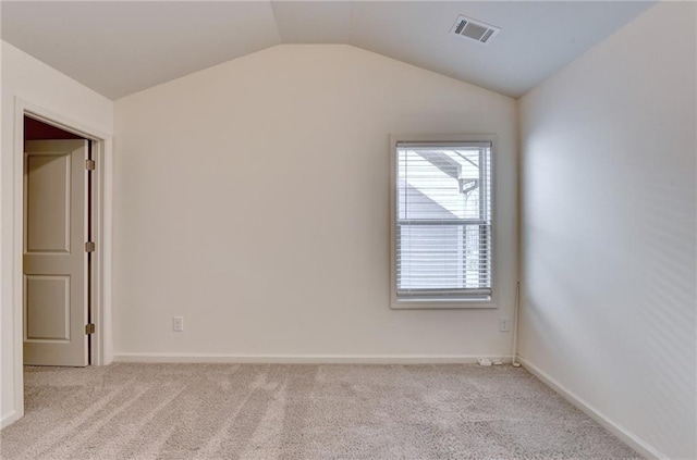 empty room with lofted ceiling, baseboards, visible vents, and light carpet