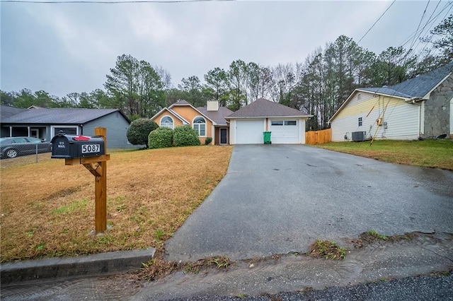 ranch-style home with cooling unit, a garage, and a front lawn