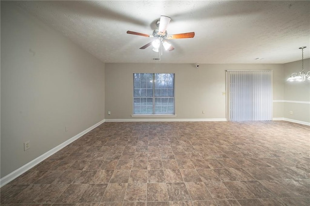 unfurnished room with ceiling fan with notable chandelier and a textured ceiling