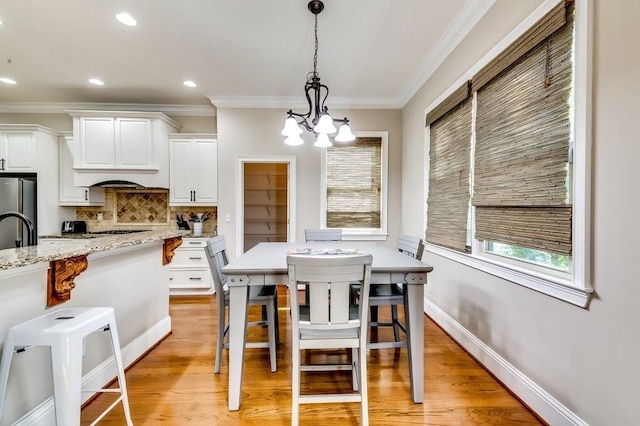 dining room featuring crown molding, an inviting chandelier, and light wood-style flooring