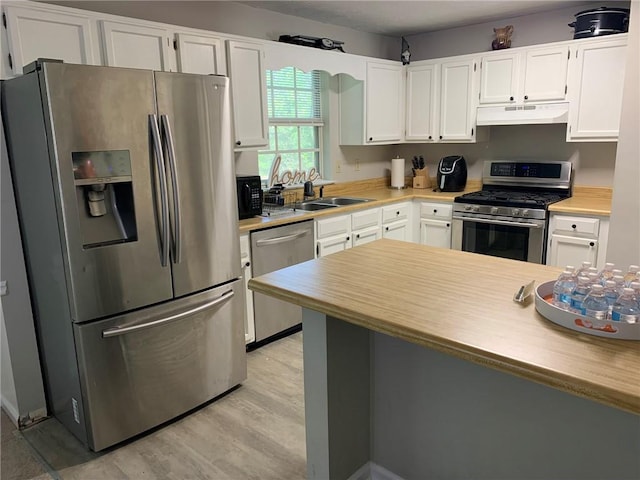 kitchen featuring a sink, light wood-style flooring, light countertops, white cabinets, and appliances with stainless steel finishes