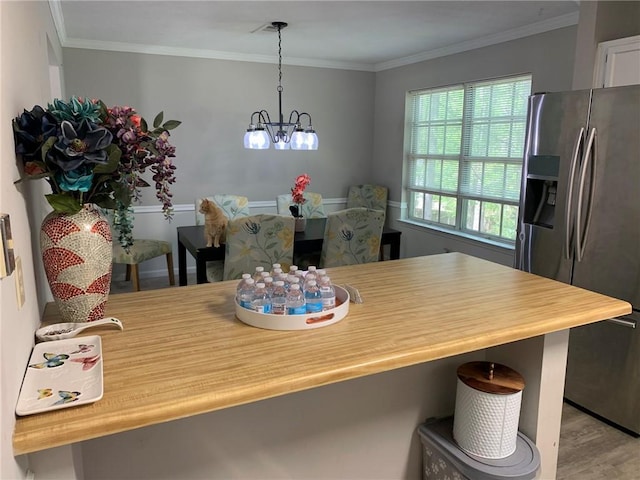 dining space with crown molding, a notable chandelier, and wood finished floors