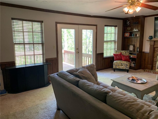 carpeted living room featuring french doors, wainscoting, a ceiling fan, and wood walls
