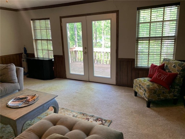 carpeted living room with wainscoting, wooden walls, french doors, and crown molding