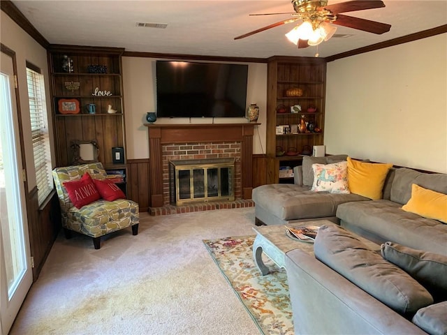 carpeted living room with crown molding, a ceiling fan, visible vents, and a fireplace