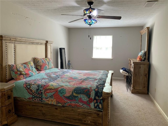 bedroom with a textured ceiling, light colored carpet, visible vents, ceiling fan, and baseboards