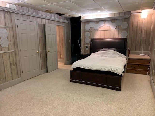 carpeted bedroom featuring baseboards, wood walls, and a drop ceiling