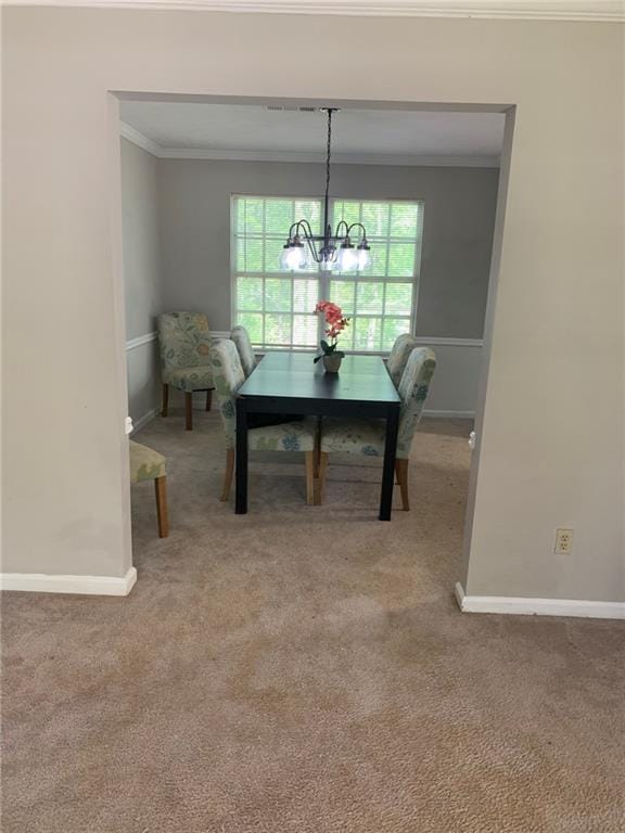 carpeted dining space with baseboards, an inviting chandelier, and crown molding
