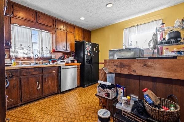 kitchen featuring stainless steel dishwasher, black fridge with ice dispenser, sink, and a textured ceiling