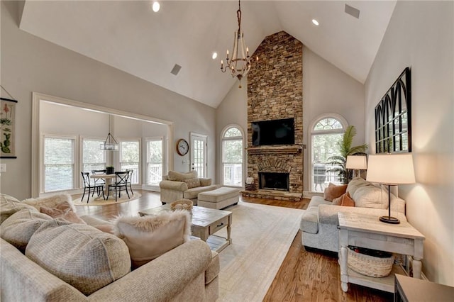 living room with a fireplace, high vaulted ceiling, a healthy amount of sunlight, and hardwood / wood-style floors