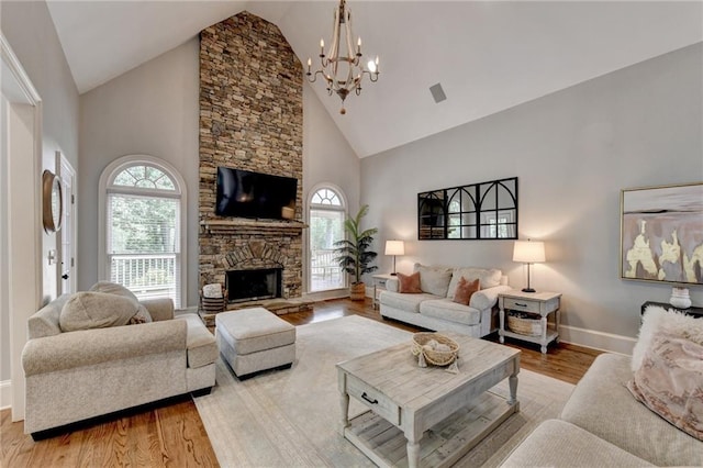 living room with high vaulted ceiling, a fireplace, hardwood / wood-style flooring, and a chandelier