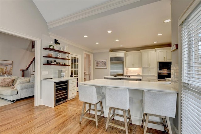 kitchen with beverage cooler, tasteful backsplash, light hardwood / wood-style flooring, and appliances with stainless steel finishes