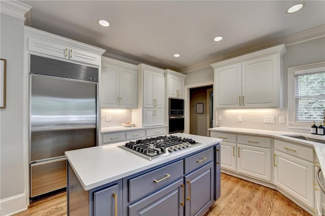 kitchen featuring appliances with stainless steel finishes, white cabinets, tasteful backsplash, and a center island