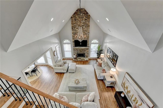 living room featuring hardwood / wood-style floors, a fireplace, brick wall, high vaulted ceiling, and a chandelier