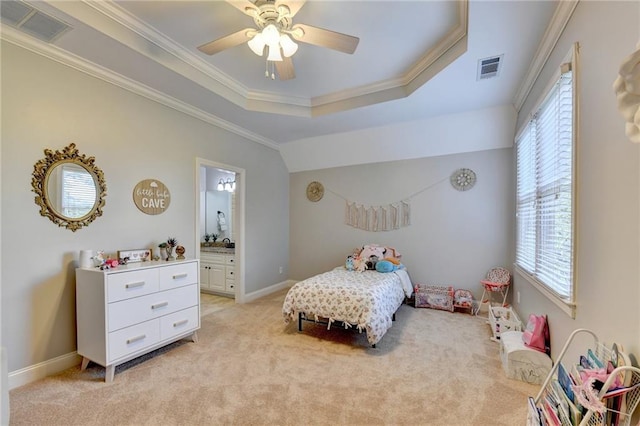 carpeted bedroom featuring a raised ceiling, ceiling fan, multiple windows, and ensuite bath