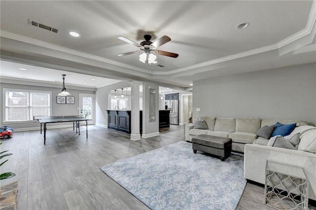 living room with ceiling fan, ornamental molding, hardwood / wood-style flooring, and a raised ceiling