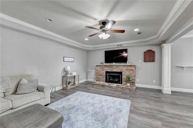 living room with ceiling fan, a tray ceiling, crown molding, a fireplace, and hardwood / wood-style flooring