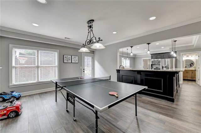 rec room with ornamental molding and light hardwood / wood-style floors