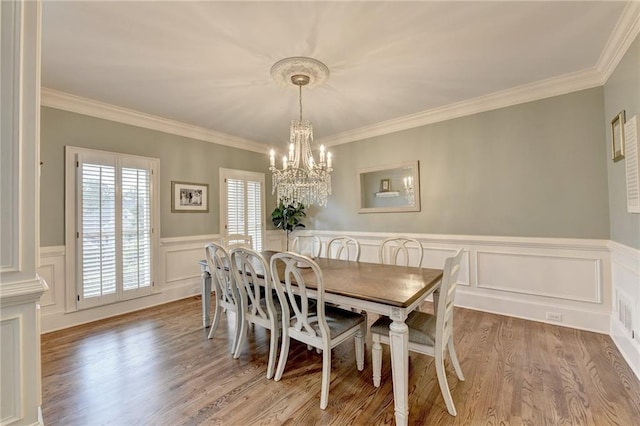 dining space with a chandelier, ornamental molding, and hardwood / wood-style floors