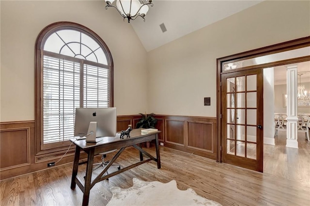 office featuring a notable chandelier, ornate columns, vaulted ceiling, and hardwood / wood-style floors