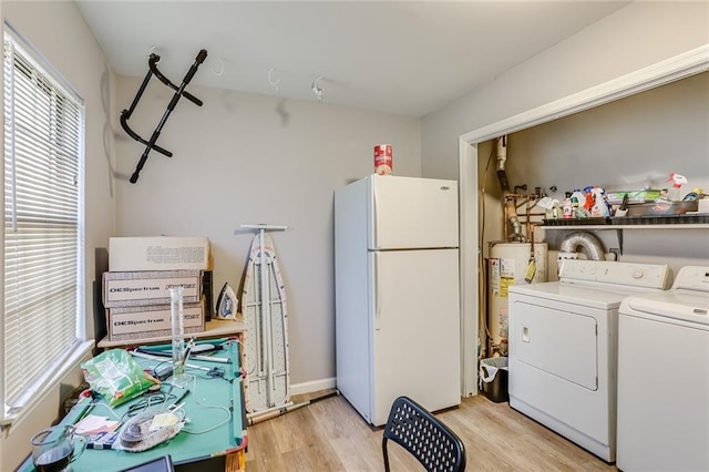 clothes washing area featuring washing machine and clothes dryer, gas water heater, and light hardwood / wood-style floors