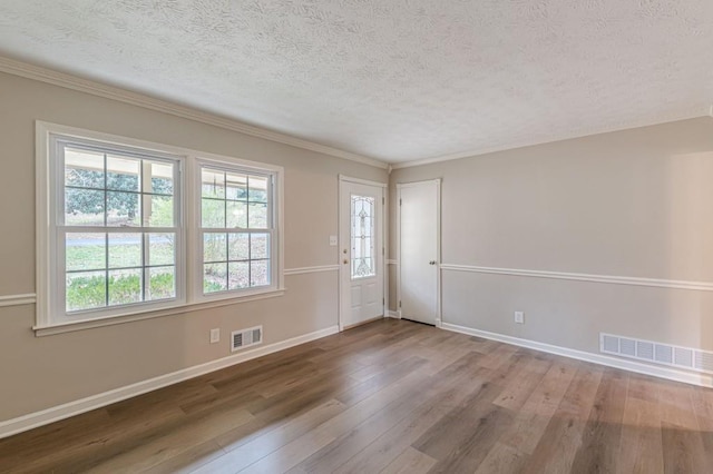 spare room with crown molding, hardwood / wood-style flooring, and a textured ceiling