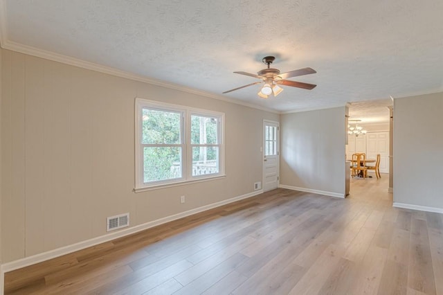 empty room featuring ceiling fan with notable chandelier, ornamental molding, light hardwood / wood-style floors, and a textured ceiling