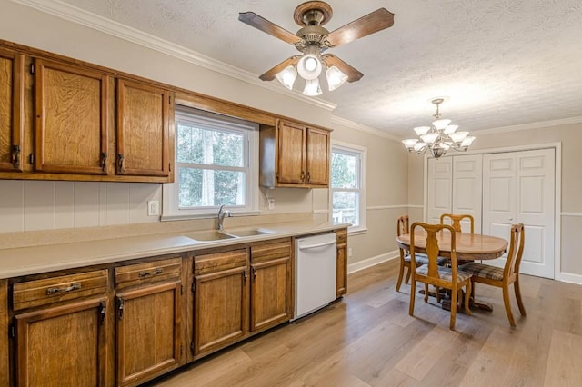 kitchen featuring pendant lighting, sink, crown molding, dishwasher, and a textured ceiling