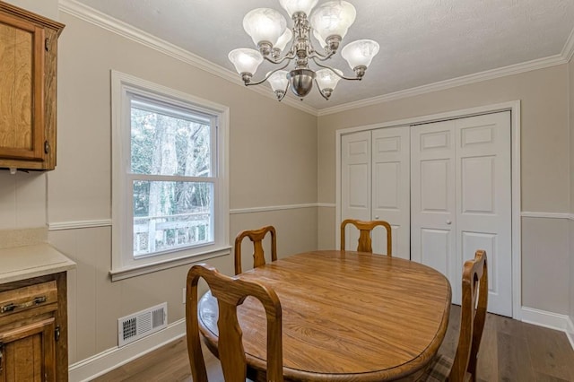 dining area featuring an inviting chandelier, hardwood / wood-style floors, and ornamental molding