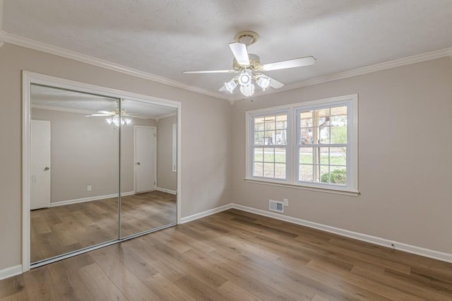 unfurnished bedroom featuring crown molding, ceiling fan, a closet, and light wood-type flooring